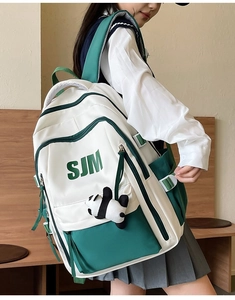 Detail view of large white and green vintage backpack with panda pendant accessory
