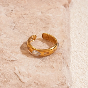 Close-up of golden sun teardrop ring with zircon stones on a natural stone surface