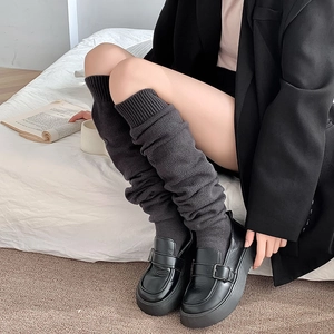 Detail of dark grey cable knit leg warmers paired with black leather platform loafers