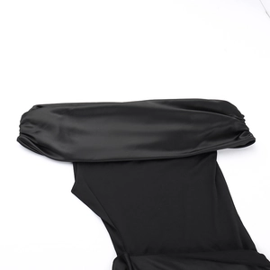 Detailed close-up of smooth black satin fabric and shoulder design of an elegant evening dress
