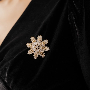 Macro detail of gold plated snowflake brooch with sparkling cubic zirconia on velvet