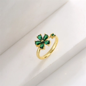 Dettaglio dell'anello dorato regolabile con fiore a cinque petali e zirconi verdi
