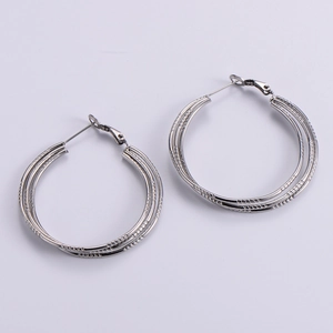 Macro shot of silver multilayered hoop earrings with textured metallic finish on white background