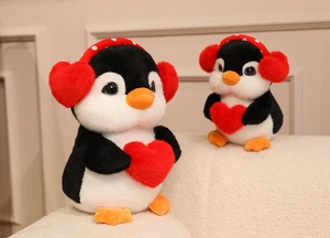 Close-up of plush penguin toys with red heart earmuffs and bow detailing in soft light