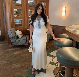 Detail of white knit maxi dress featuring blue denim trim and elegant button V-neckline