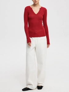 Slim fit red long sleeve V-neck knitted top styled with white wide-leg trousers on model