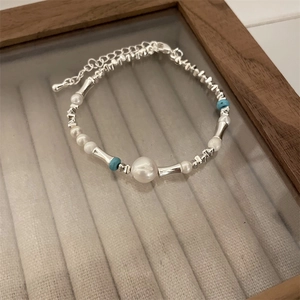 Detail of silver beaded heart bracelet with pearls and blue stones in a jewelry box