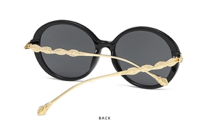 Detail view of stylish oversized sunglasses featuring golden leaf-shaped metal temples