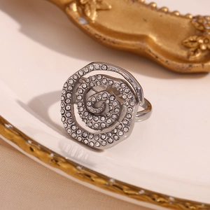 Macro shot of a silver spiral rose ring with pave crystals on a vintage ceramic plate