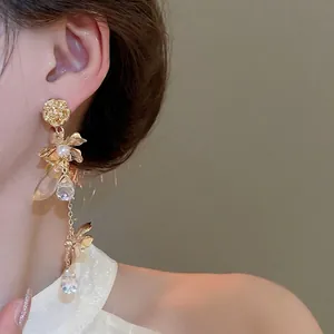 Elegant gold flower tassel earrings with pearls and crystals worn by a model
