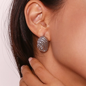 Close-up of a silver twisted texture ball earring on model ear showing metallic detail
