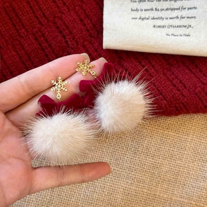 Detail of red bow earrings with golden snowflake and soft white faux fur pompoms