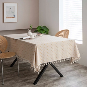 Detail of cotton linen tablecloth with yellow floral pattern and elegant fringe edges