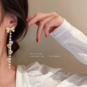 Boucles d'oreilles nœud élégantes avec perles blanches et cristaux sur un mannequin