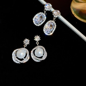 Detail of silver earrings with sparkling cubic zirconia crystals and white faux pearls