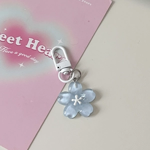 Detail of blue cherry blossom resin keychain with white lobster clasp on pink card