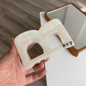 Detail of cream-colored square acetate hair claw clip featuring black Bry lettering text