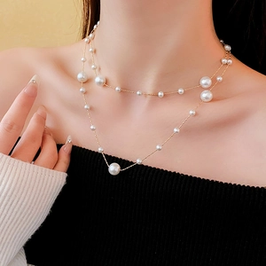 Detail view of double-layered gold plated necklace with white pearls on a female model