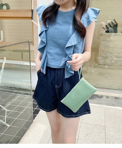 Pale green crocodile embossed clutch bag with wristlet strap held by a stylish model