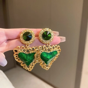 Close-up of vintage gold heart earrings with green rhinestones shown in hand