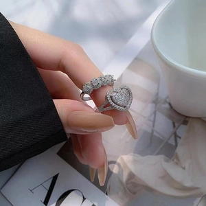 Detail of silver heart-shaped and three-stone rings worn for elegant jewelry display