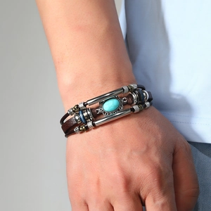 Close-up of vintage multi-layer brown leather bracelet with turquoise bead on male wrist