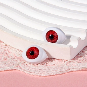 Macro shot of 14x19mm boat-shaped doll eyes with red irises on pink lace background