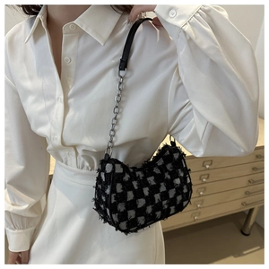 Detail of tweed checkered crossbody bag featuring silver chain and black leather strap