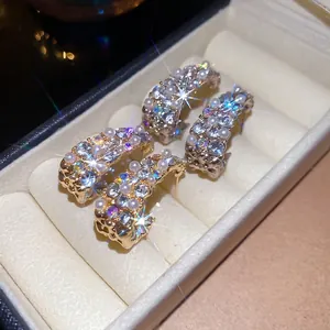 Elegant gold-tone C-shaped hoop earrings with sparkling rhinestones and white pearls