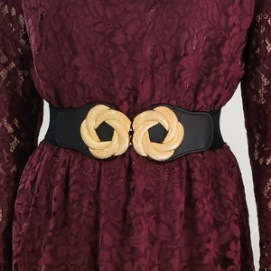 Women's wide elastic waist belt with ornate gold relief buckle on a lace dress