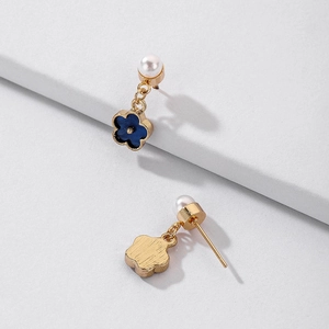 Detailed macro of gold flower earrings with klein blue petals and white faux pearls