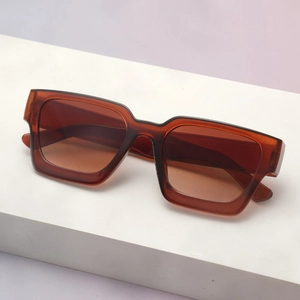 Detailed view of square thick frame sunglasses in amber on a geometric display stand