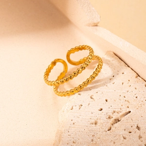Detail of a gold titanium steel double-layer beaded open ring on a stone texture