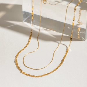 Double layered gold necklace featuring an oval link chain and a sleek snake bone chain