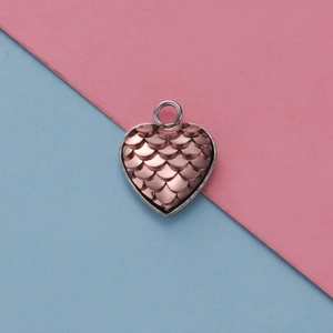 Dettaglio macro del ciondolo a cuore in oro rosa con motivo unico a squame di pesce