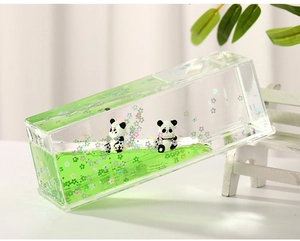 Macro view of panda figurine inside liquid hourglass with green oil and floral glitter