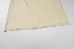 Close-up of beige knit dress hem showing precise stitching and breathable fabric texture