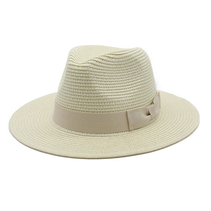 Close-up of beige woven straw fedora hat with light brown ribbon and bow detail