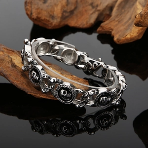 Macro detail of gothic skull link bracelet in polished steel on dark wood background