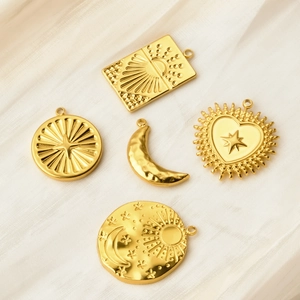 Detail of five gold-plated stainless steel pendants with sun, moon and star celestial motifs