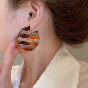 Close-up of vintage C-shaped wood resin striped earrings worn by a female model