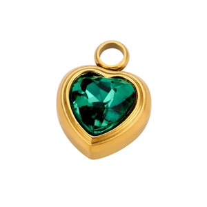 Detailed macro view of vintage gold heart pendant with emerald green faceted gemstone