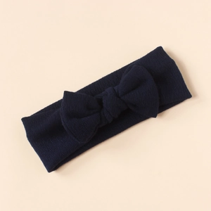 Detailed close-up of dark blue knit bow headband for infants on beige background