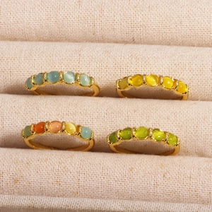 Detail of four colorful zircon gemstone rings in a linen jewelry box display