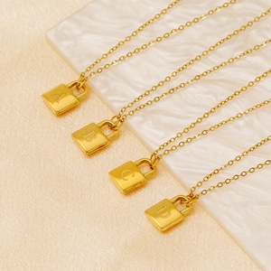 Gold titanium steel necklaces with square initial padlock pendants on marble and silk surface