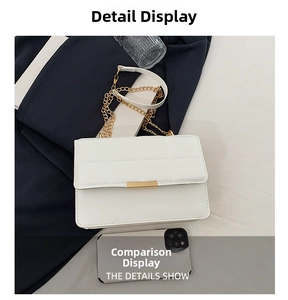 Close-up of white quilted chain bag with gold lock next to smartphone for size comparison
