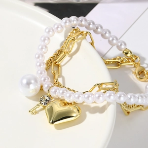 Close-up of baroque pearl layers with golden heart and diamond-set key pendants