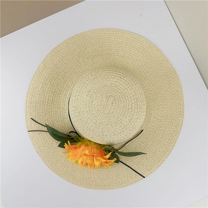 Vue à plat d'un chapeau de soleil beige à large bord avec tournesol et ruban noir