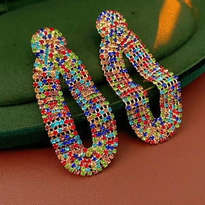 Close-up of vintage gold U-shaped earrings with colorful zircon on green velvet stand
