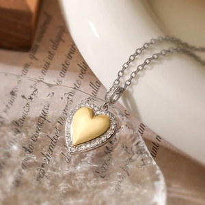 Macro shot of gold and silver heart pendant necklace with zircon inlay on vintage background